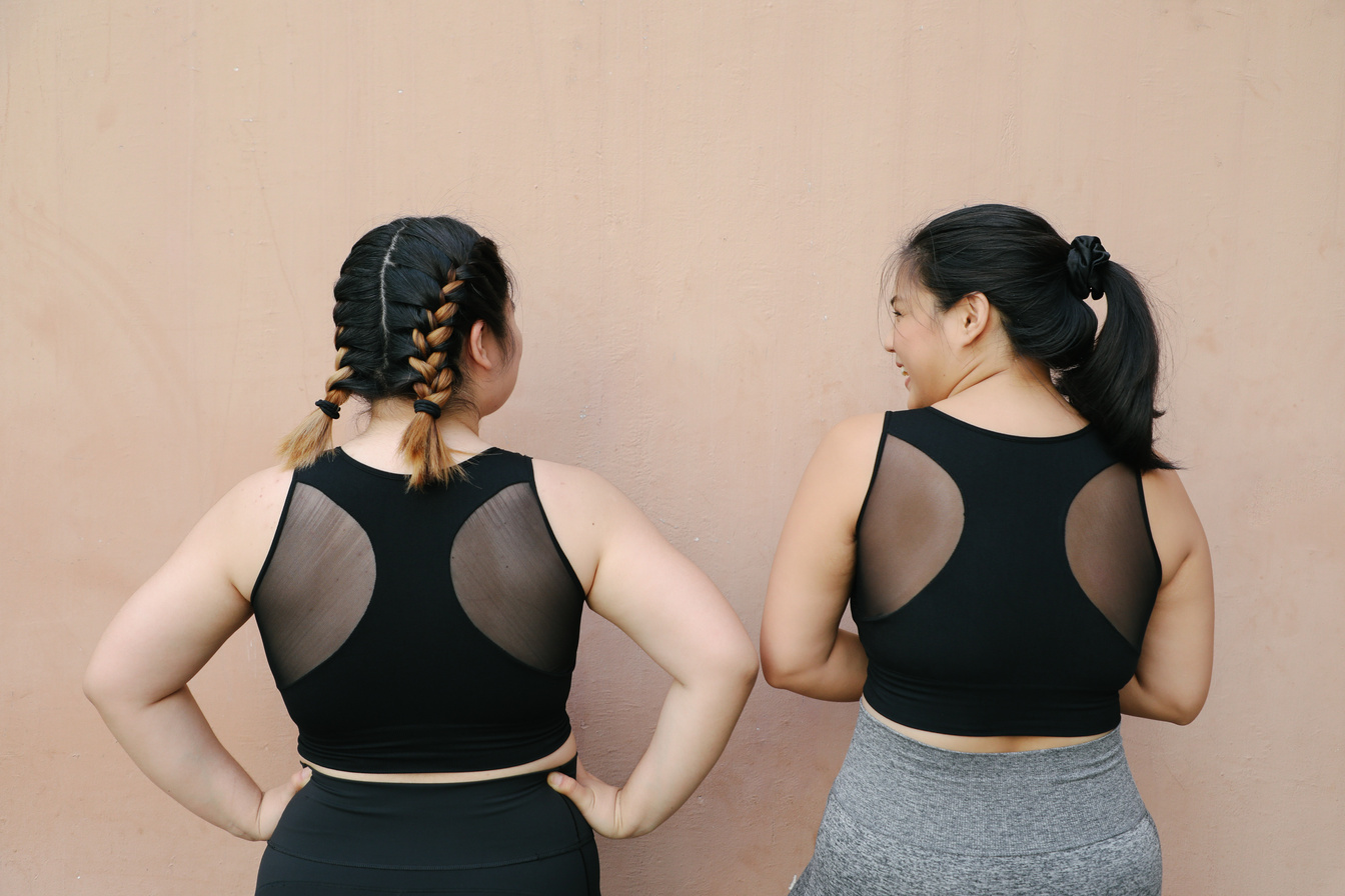 Two women in activewear with backs facing the camera